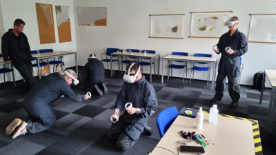Studenten zitten op handen en knieën met een VR-bril op om een voertuig virtueel te onderzoeken