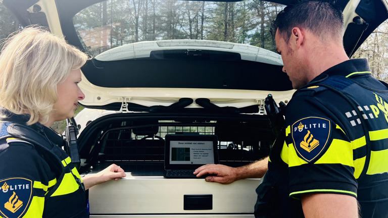 Student Rianne staat bij de open achterklep van een politieauto