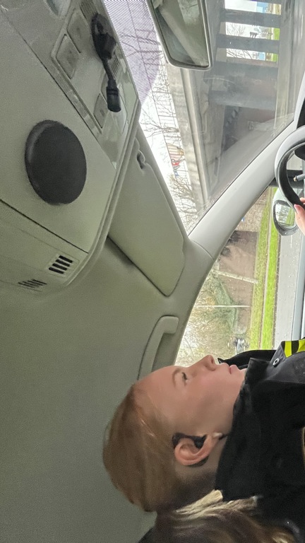 Student Pam achter het stuur in een politiebusje