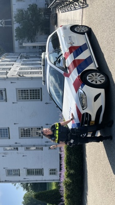 Student Linda staat voor een wit pand bij een politieauto