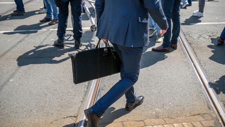 Een man met een handtas loopt over straat