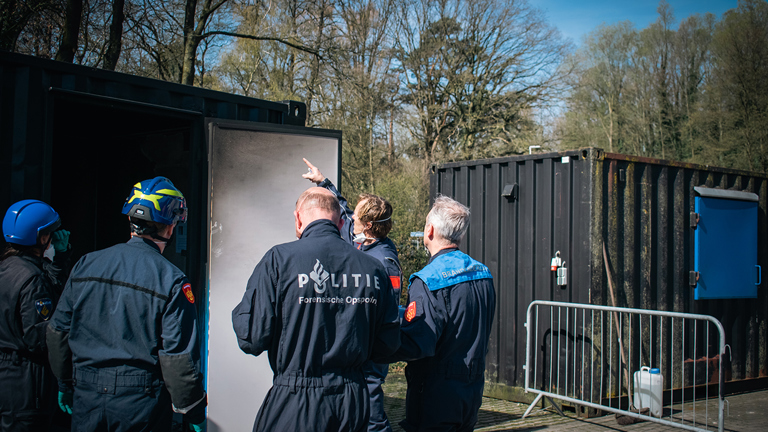 Groepje studenten brandonderzoek staan buiten een uitgebrande container