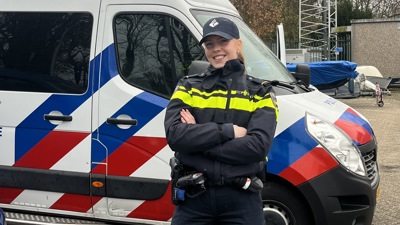 Student Pam in uniform voor een politiebusje