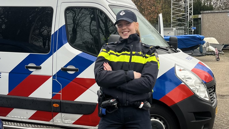 Student Pam in uniform voor een politiebusje