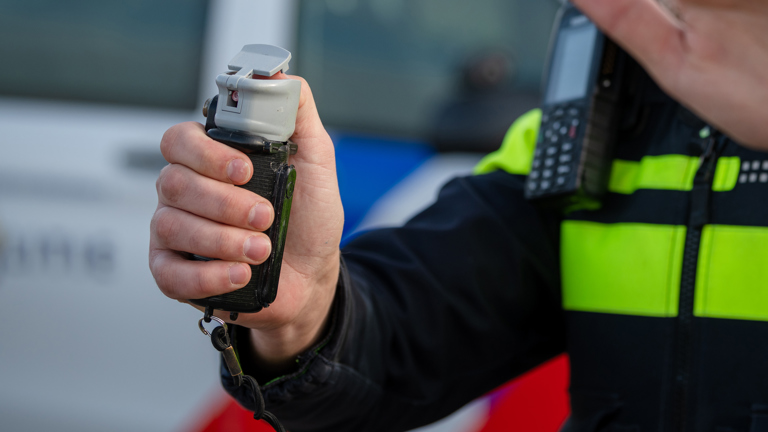 Een agent houdt een bus pepperspray vast