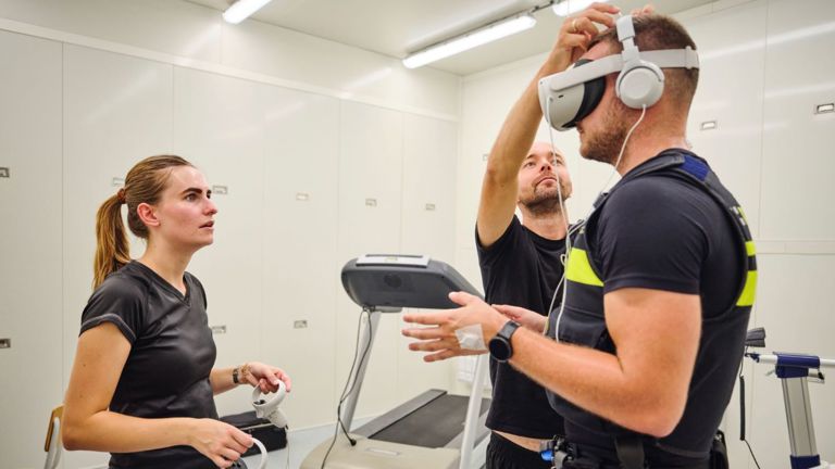 Student Tom staat in de klimaatkamer en krijgt een VR-bril op