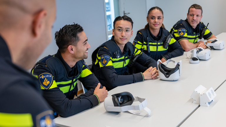 Een groep studenten zit aan tafel en hebben VR-brillen voor zich liggen