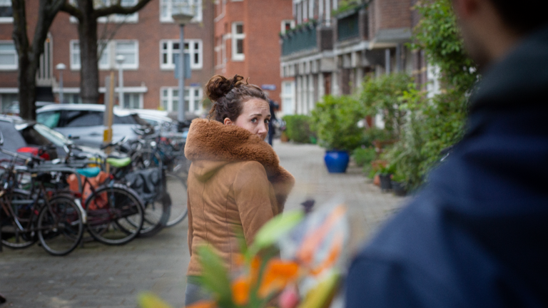 Stalking - A girl looks back in alarm and sees a man with flowers approaching