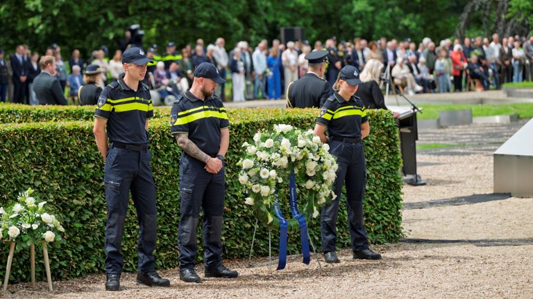 Drie politiestudenten staan naast een krans in de Tuin van Bezinning