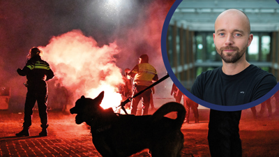 Een hondengeleider en hond staan bij vuurwerk