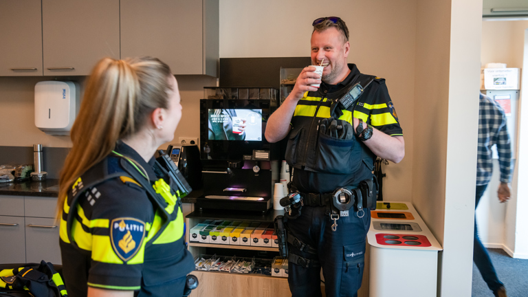 Twee politiestudenten in uniform staan bij een koffiezetapparaat