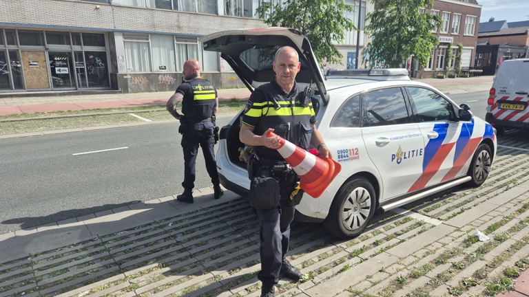 Praktijkbegeleider Jan staat bij een politieauto met een pion in zijn hand