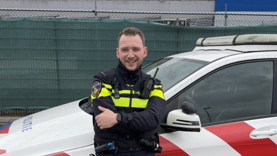 Student Danyel in uniform voor een politieauto