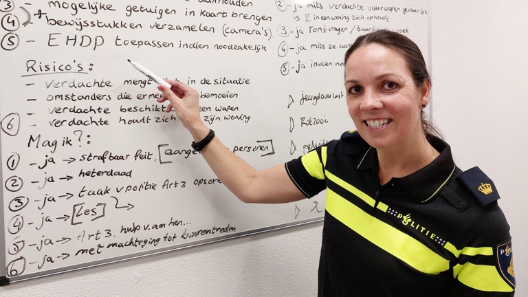 Docent Miranda staat bij een whiteboard en wijst tekst aan