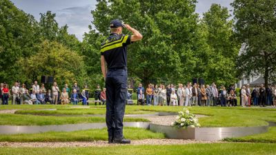 Een politiestudent salueert bij het monument Tuin van Bezinning