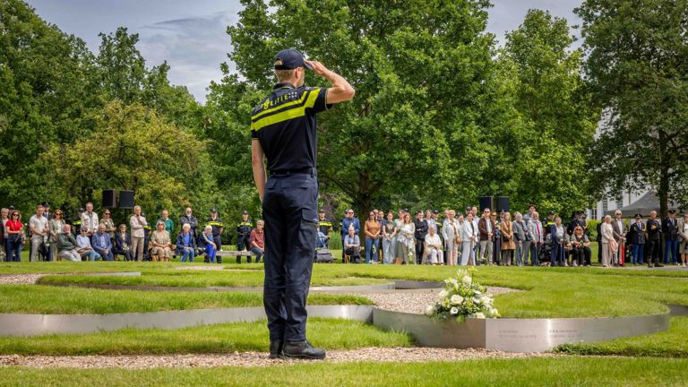 Een politiestudent salueert bij het monument Tuin van Bezinning
