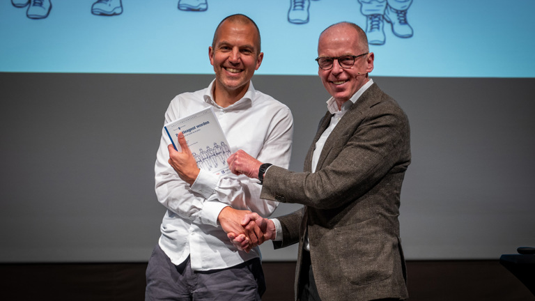 Het boek 'Politieagent worden' wordt overhandigd aan Leonard Kok