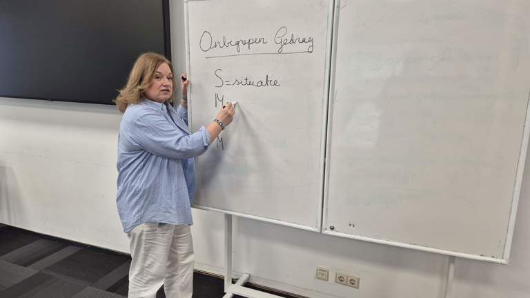 Docent Esther staat voor een schrijfbord in een klaslokaal