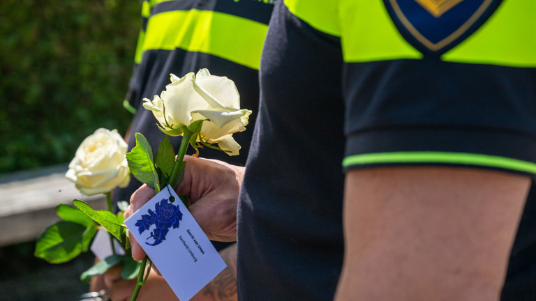Twee politiestudenten houden een witte roos vast in hun hand