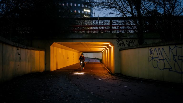 Een fietstunnel waar een vrouw doorheen fietst terwijl het donker is