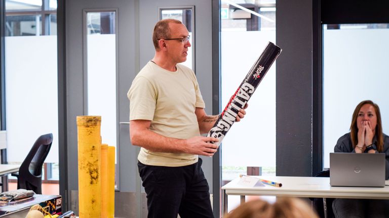 Docent Ferry houdt een groot stuk vuurwerk vast in de les