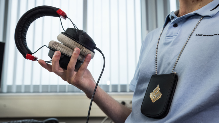 Een agent zit in de telefoon tapkamer met een koptelefoon in zijn hand