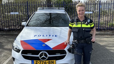 Marianne leunt in uniform tegen een politieauto