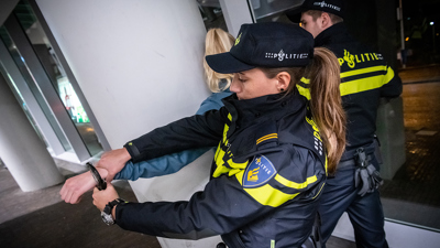 Twee politieagenten slaan een dame in de boeien