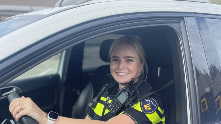 Student Lisa achter het stuur van een politieauto