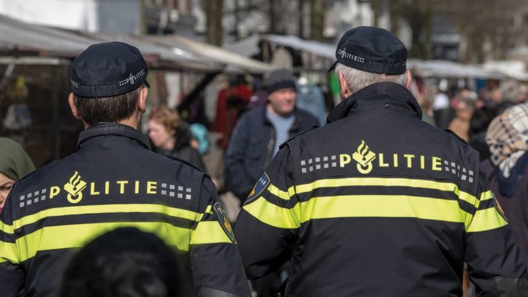 Politiewerk in verre uithoeken - Twee agenten op de rug gezien lopen op markt