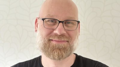 Docent Tim lacht naar de camera met zijn armen over elkaar