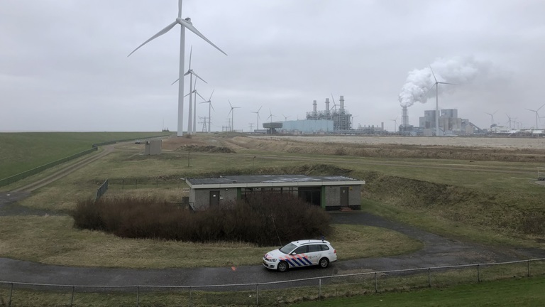 Een politieauto in een uitgestrekt gebied met windmolens