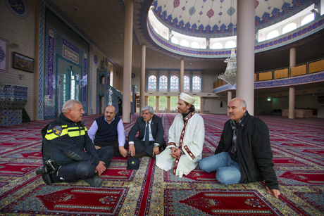 wijkagent en imams zittend in moskee